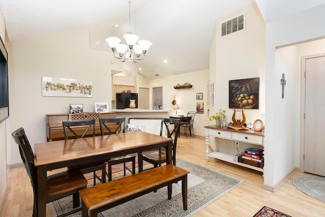 dining space featuring a chandelier, high vaulted ceiling, visible vents, baseboards, and light wood finished floors