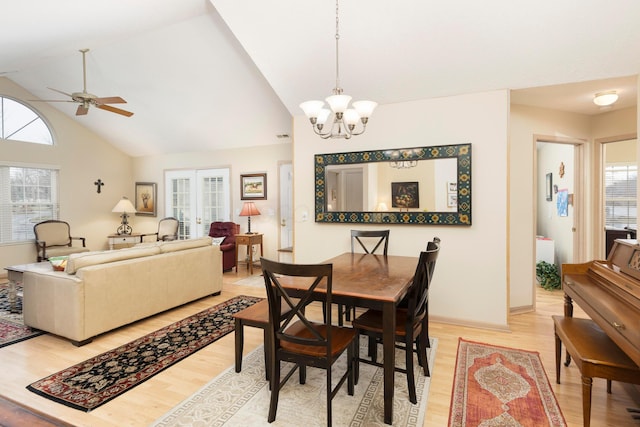 dining space with light wood-type flooring, ceiling fan with notable chandelier, a wealth of natural light, and french doors