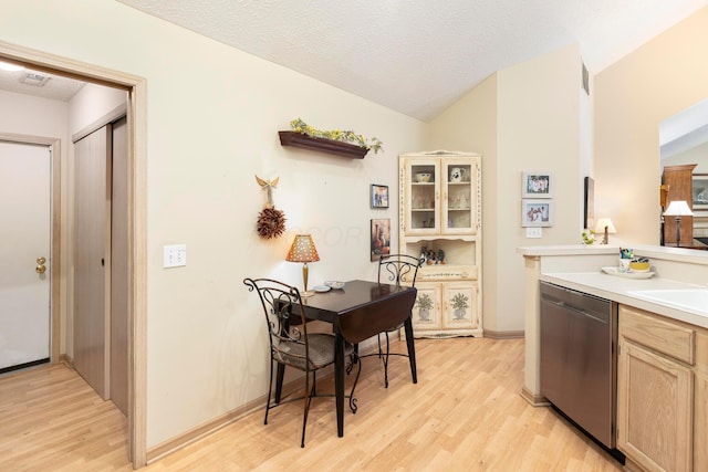 kitchen with light wood finished floors, a textured ceiling, light countertops, and dishwasher