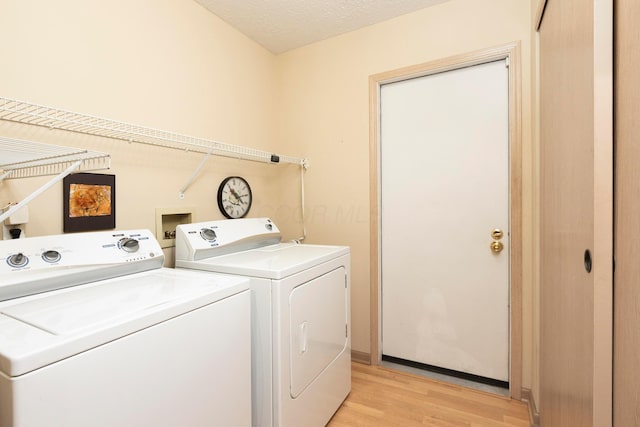 laundry area with laundry area, a textured ceiling, light wood-style floors, and washer and dryer