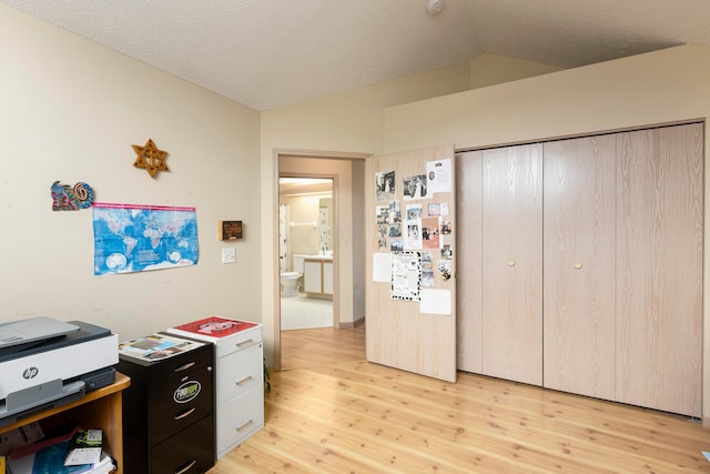 office with vaulted ceiling, a textured ceiling, and light wood-type flooring