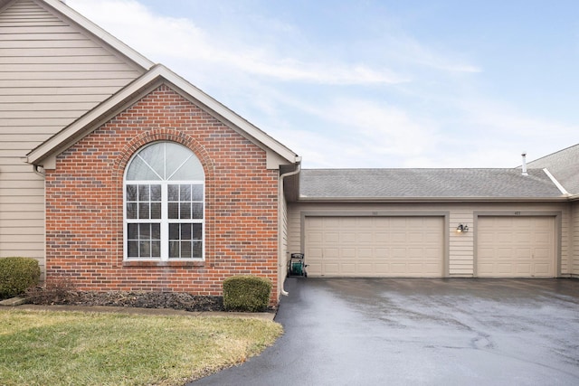 view of front of property with an attached garage, aphalt driveway, and brick siding