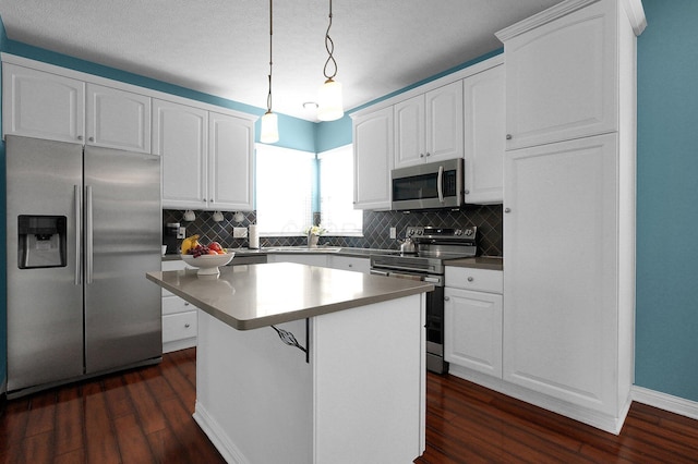 kitchen featuring appliances with stainless steel finishes, a kitchen island, decorative light fixtures, and white cabinets