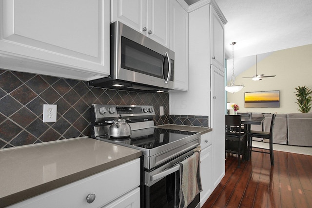 kitchen featuring dark wood finished floors, white cabinets, dark countertops, appliances with stainless steel finishes, and backsplash