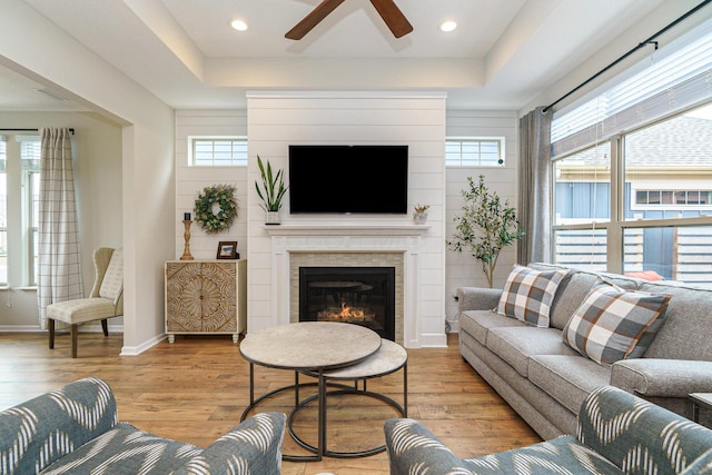 living room featuring recessed lighting, light wood-type flooring, baseboards, and a glass covered fireplace