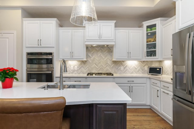 kitchen with backsplash, white cabinets, stainless steel appliances, and a sink