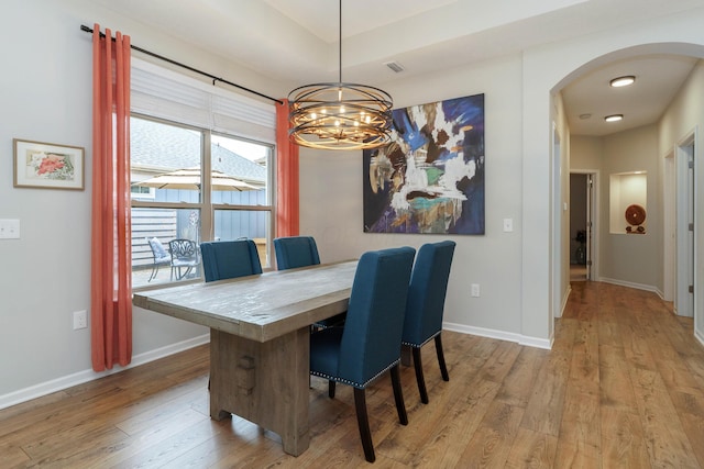 dining space with arched walkways, visible vents, baseboards, and wood finished floors