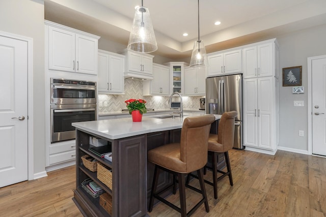 kitchen with a sink, stainless steel appliances, hardwood / wood-style floors, and white cabinets