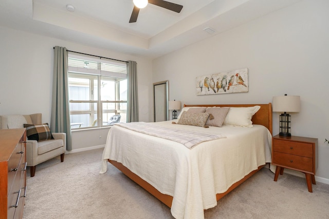 bedroom featuring light carpet, visible vents, baseboards, and a tray ceiling