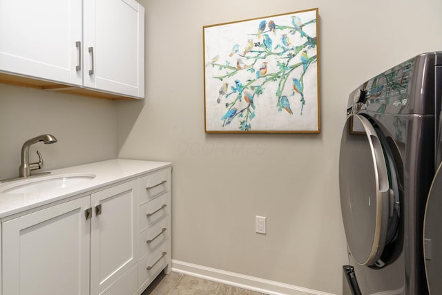 laundry area with a sink, cabinet space, light tile patterned flooring, baseboards, and washing machine and clothes dryer