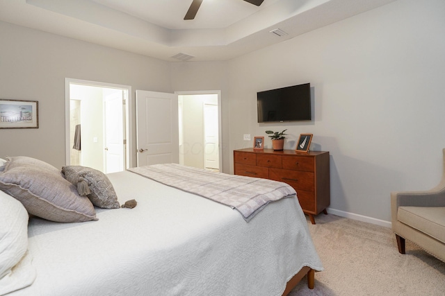 bedroom with visible vents, light carpet, a tray ceiling, ensuite bath, and baseboards