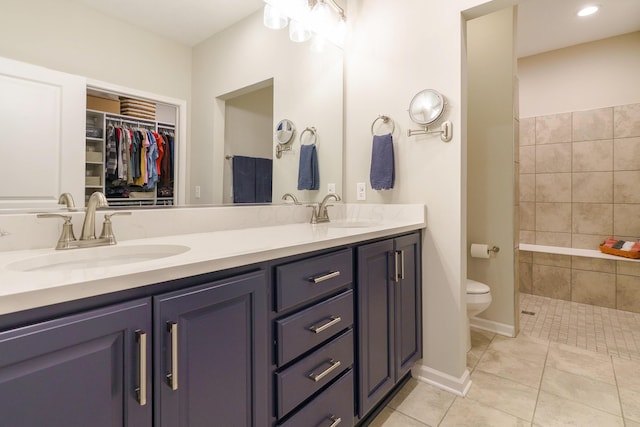 bathroom with double vanity, tile patterned floors, toilet, and a sink