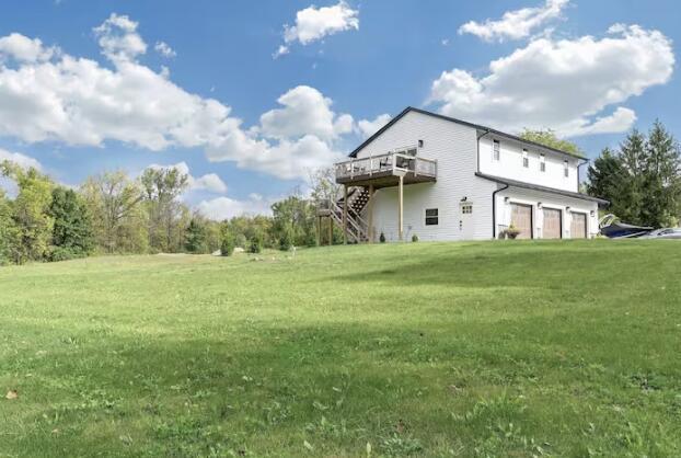 back of house featuring a garage, a lawn, stairway, and a wooden deck