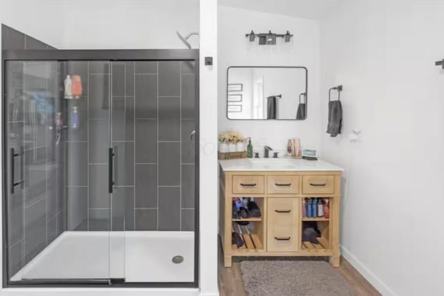 bathroom featuring baseboards, vanity, a shower stall, and wood finished floors