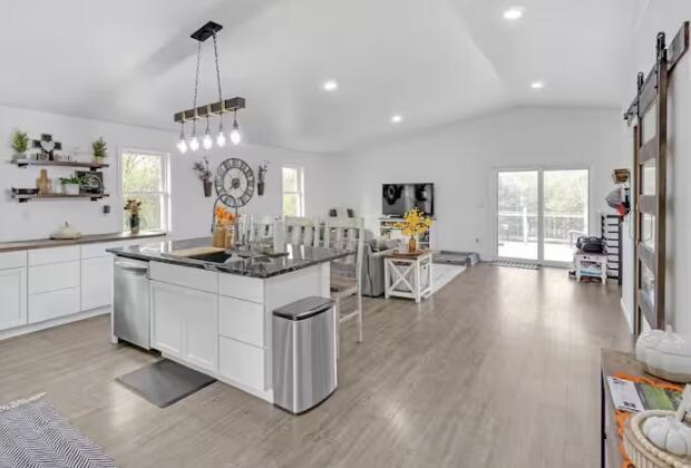 kitchen featuring a barn door, white cabinets, stainless steel dishwasher, a center island, and dark countertops