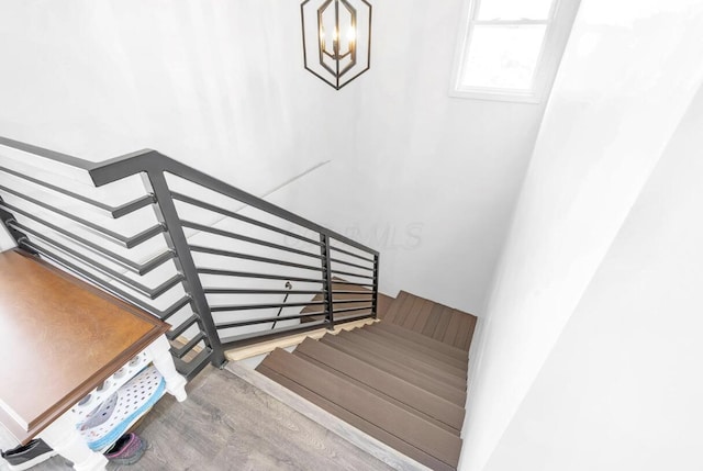 stairs featuring wood finished floors and a notable chandelier