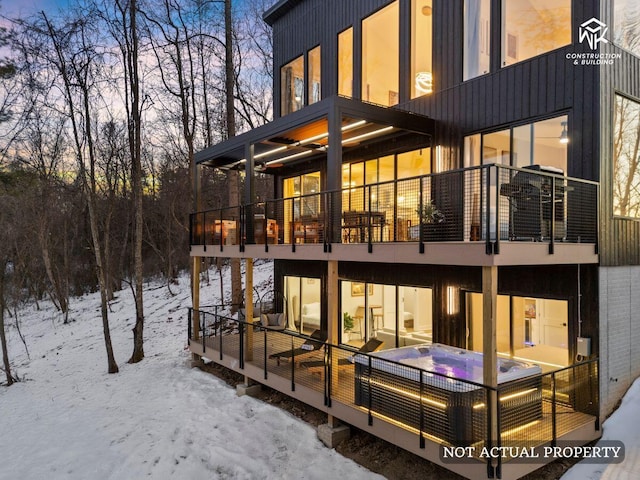 snow covered property featuring a hot tub and a balcony