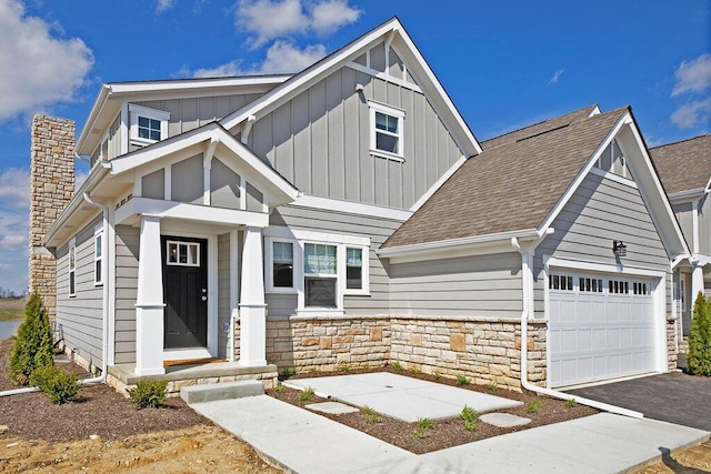 view of front of home with a garage, a chimney, aphalt driveway, roof with shingles, and board and batten siding