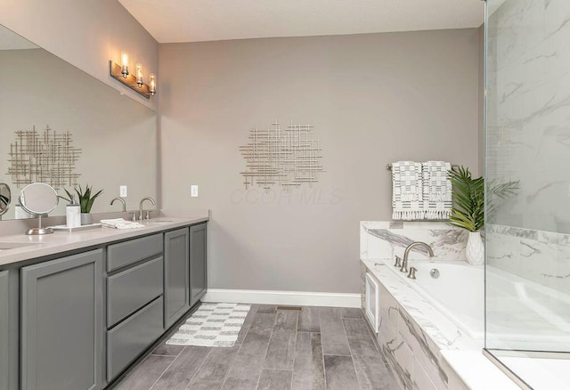 full bathroom featuring double vanity, baseboards, a garden tub, wood tiled floor, and a sink