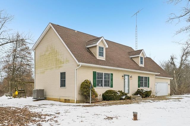 cape cod house with a garage, central AC unit, and roof with shingles