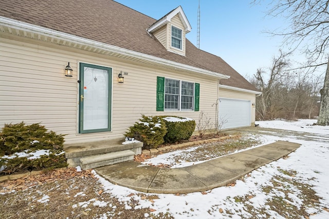 view of front facade featuring entry steps, a shingled roof, and a garage