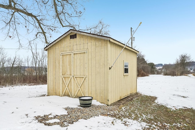 snow covered structure featuring a storage shed and an outdoor structure