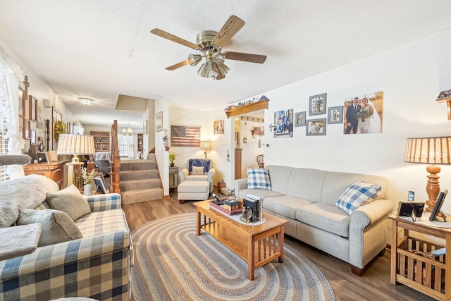 living room featuring wood finished floors, ceiling fan, and stairs