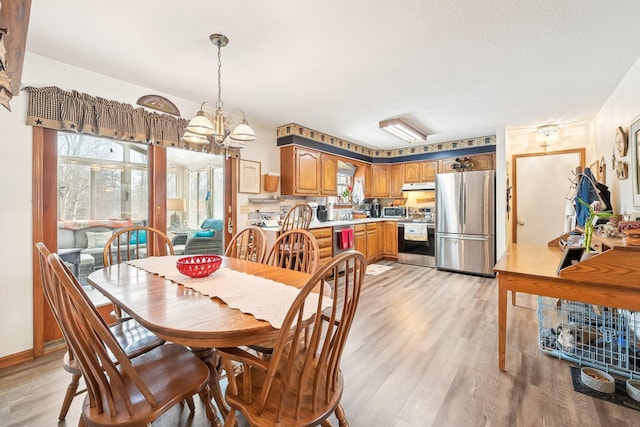 dining space featuring light wood-style floors, a toaster, and a notable chandelier