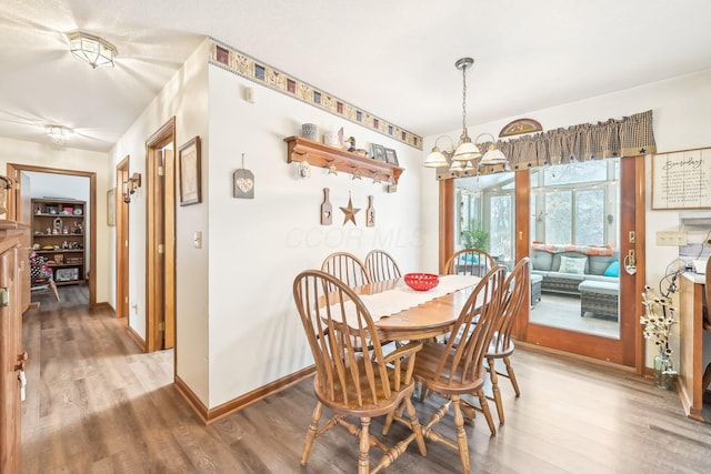 dining space with baseboards, a chandelier, and wood finished floors