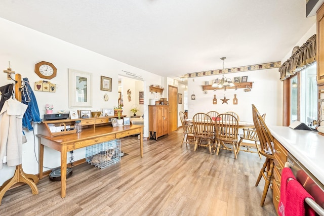 dining area featuring a chandelier, baseboards, and light wood finished floors