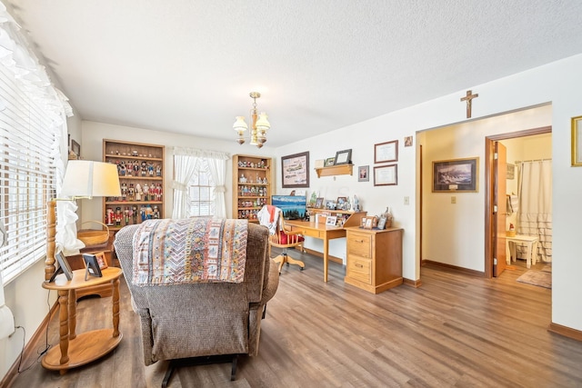 office area featuring a chandelier, a textured ceiling, baseboards, and wood finished floors