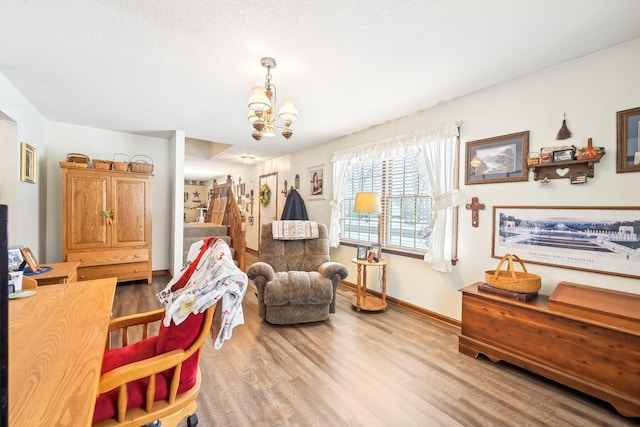 living area featuring a chandelier, stairway, baseboards, and wood finished floors