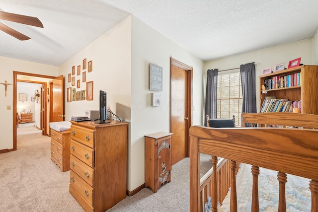 bedroom featuring light carpet, a textured ceiling, and baseboards