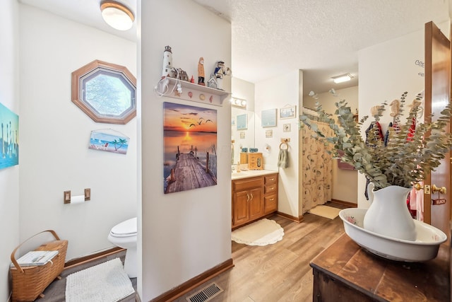 full bathroom with visible vents, a textured ceiling, vanity, wood finished floors, and baseboards