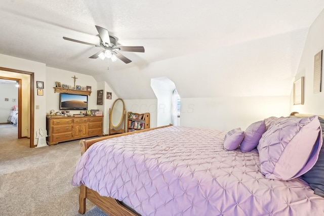 bedroom featuring lofted ceiling, a textured ceiling, a ceiling fan, and light colored carpet