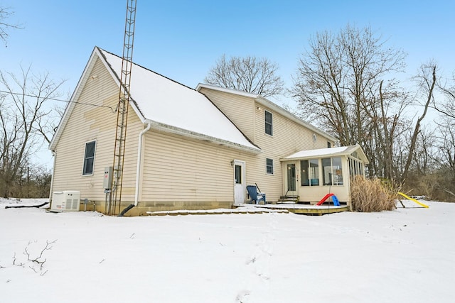 snow covered rear of property featuring a sunroom