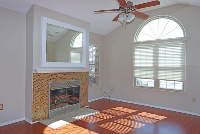 unfurnished living room featuring lofted ceiling, a tiled fireplace, and wood finished floors