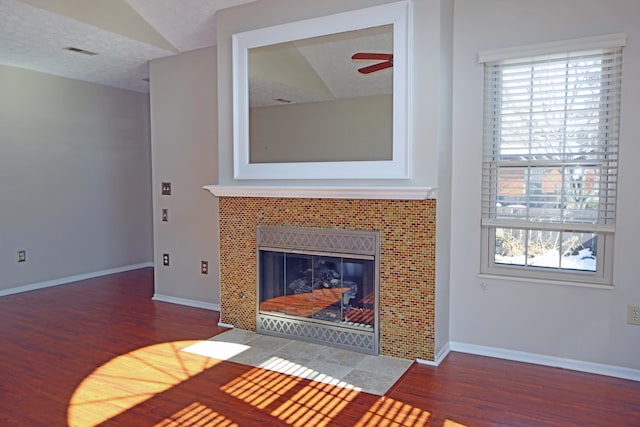 unfurnished living room with a textured ceiling, wood finished floors, visible vents, and baseboards