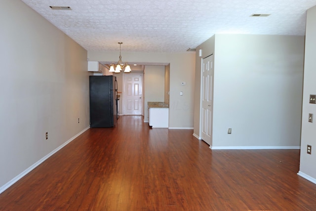 unfurnished room with baseboards, visible vents, a chandelier, and dark wood-type flooring