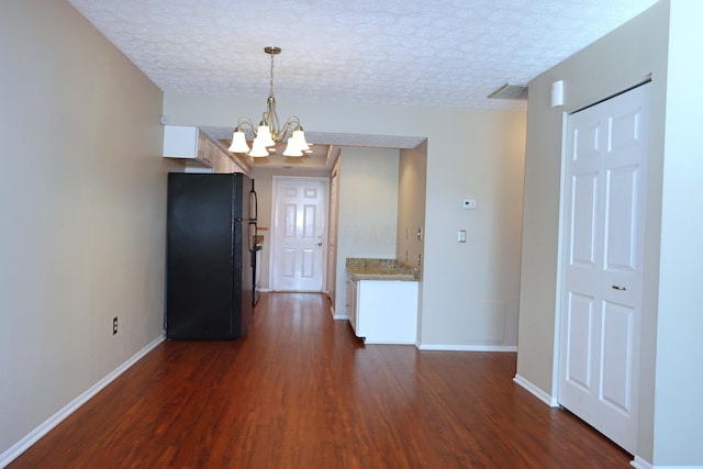 interior space featuring dark wood-style floors, visible vents, a textured ceiling, and an inviting chandelier