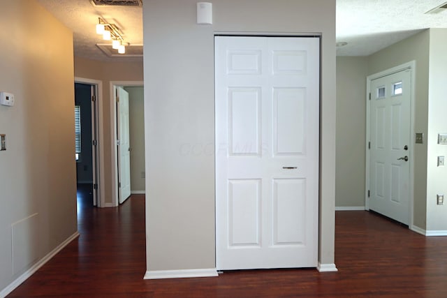 hallway with a textured ceiling, wood finished floors, and visible vents