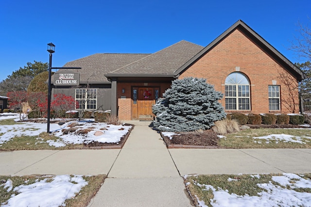 view of front of property with a shingled roof and brick siding