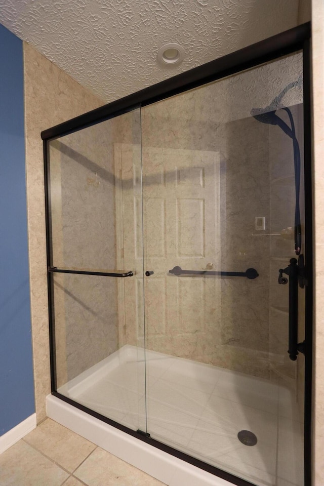 full bathroom with a shower stall, a textured ceiling, and tile patterned floors