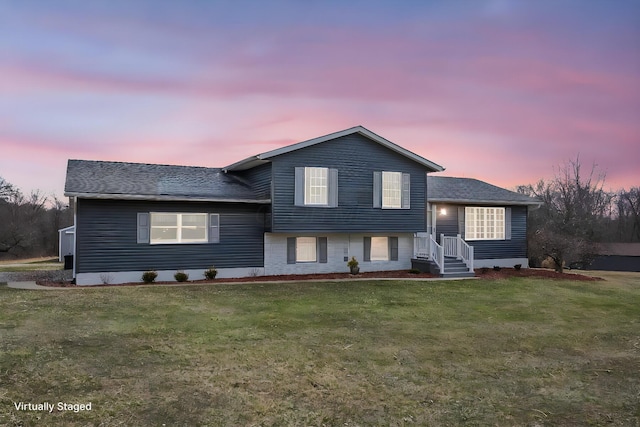 tri-level home with a front yard, brick siding, and a shingled roof