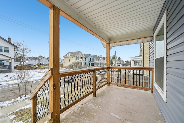 snow covered back of property with a residential view and covered porch