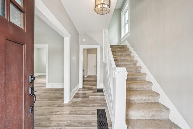 entryway with light wood-type flooring, visible vents, stairs, and baseboards