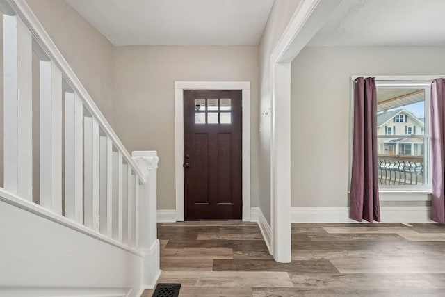 entryway with stairway, wood finished floors, a wealth of natural light, and baseboards