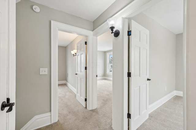 hallway with light colored carpet and baseboards