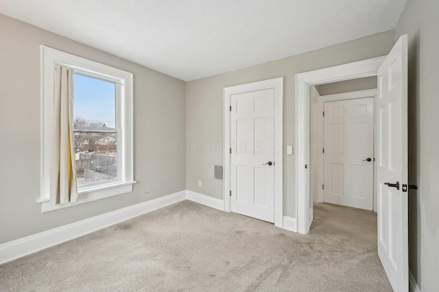 unfurnished bedroom with light carpet, visible vents, and baseboards