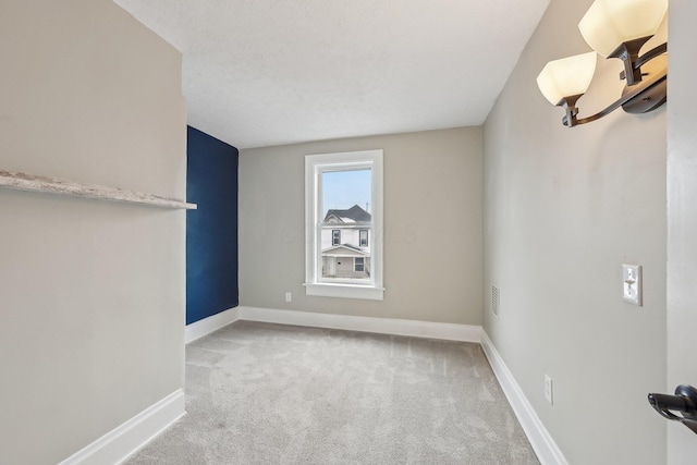 spare room with baseboards and light colored carpet